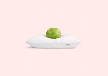 Una almohada blanca de Dorma con una manzana verde encima, sobre fondo rosa pálido