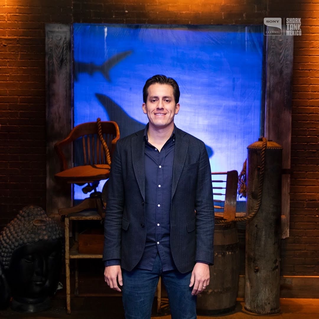 Edgar Temores de saco oscuro en el foro de Shark Tank México, con el tiburón azul del decorado detrás