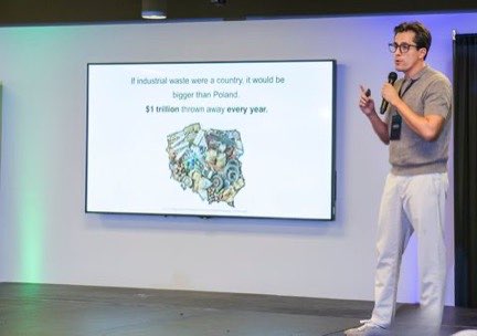 Edgar Temores presentando ante una diapositiva que compara el residuo industrial con un país y cifra un billón de dólares tirados cada año