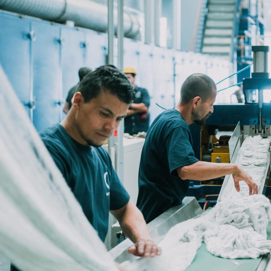 Operarios de Technofibers manipulando fibra textil recién producida en la línea