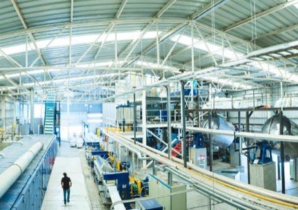 Vista elevada de la nave de producción, con las líneas a ambos lados y una persona caminando por el pasillo central
